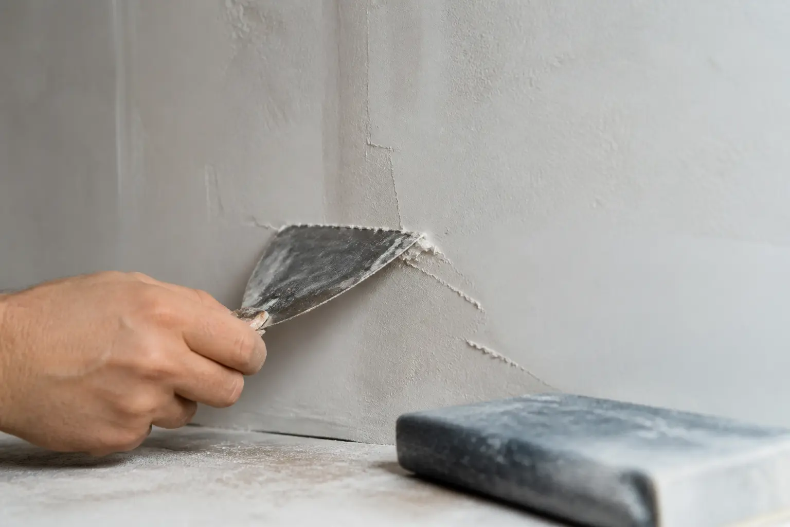 Lisser un enduit sur un mur intérieur avec couteau à enduire, ponçage fin et surface prête à peindre.