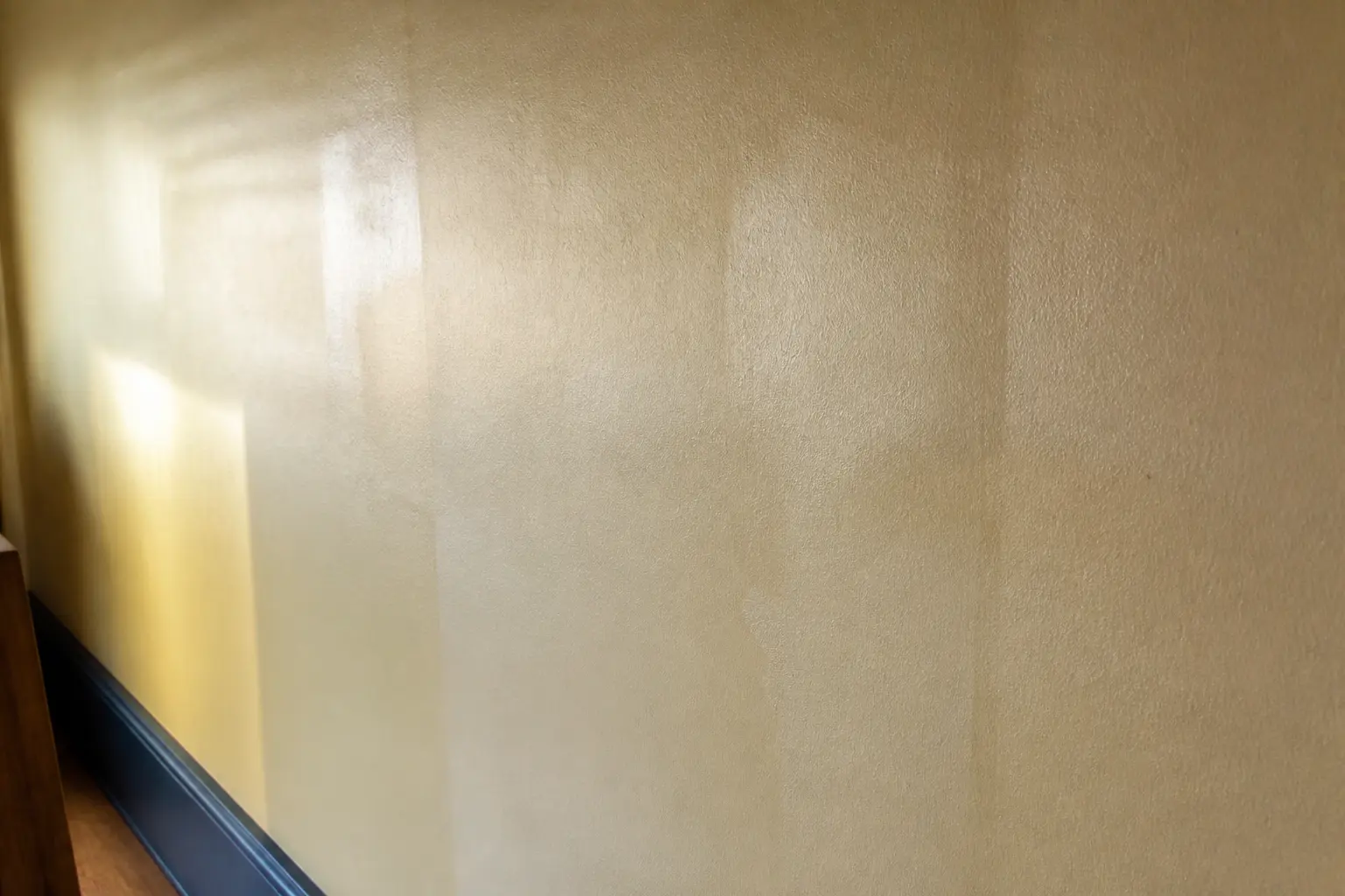 3 couches de peinture et toujours des traces sur un mur de salon, avec marques de rouleau et reflets irréguliers au soleil